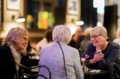 Photograph of three people socializing while sitting at a table.