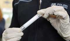 Полицейский держит ватную палочку для взятия образцов ДНК. Фото: Stefan Puchner / EPA