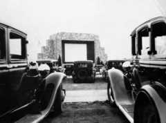 a black and white photograph of automobiles parked in front of the drive-in movie screen in Camden