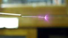 Photograph of corona discharge from a wire taken in room light.