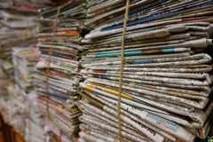 Bundles of newspapers, laid flat in piles and tied together.