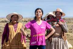 Darleyn stands with arms on her hips with women from her community. 