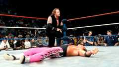 The Undertaker on one knee beside Bret Hart as he lay flat on his back