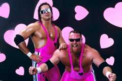 The Hart Foundation posing in front of pink hearts in their signature hot pink costumes