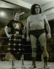 Andre the Giant and Rowdy Roddy Piper standing inside a ring and smiling