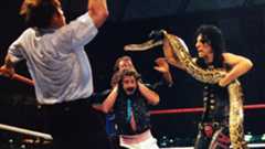 Alice Cooper spooks the referee with Damien the Snake at WrestleMania III while Jake Roberts applies a Full Nelson on Jimmy Hart.
