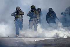Federal agents point weapons and fire tear gas at protesters in Minneapolis on Saturday after a man was shot dead by a federal immigration agent. (Stephen Maturen/Getty Images)