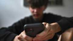 A teenager uses his mobile phone to access social media in Sydney, Australia, on November 13, 2024.
