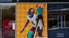 La NFL generó el año pasado unos 23.000 millones de dólares, una cifra que cuadruplica los ingresos de competiciones como LaLiga o la Premier League. Aunque muchos aficionados en España no sigan de cerca este deporte, lo cierto es que se trata de la liga con mayor facturación del planeta, por encima incluso de gigantes como la NBA o la MLB, que ronda los 11.000 millones. Su dominio económico es abrumador y, desde esa posición privilegiada, la NFL continúa impulsando su expansión internacional. Ya ha organizado encuentros oficiales en cinco países —Reino Unido, Irlanda, Brasil, Alemania y México— y ahora desembarca en España con un ambicioso proyecto en el estadio Santiago Bernabéu. La inversión aproximada es de dos millones de dólares, una cantidad mínima para sus estándares, destinada a transformar el coliseo madridista en un auténtico espectáculo de fútbol americano.Este domingo, los Miami Dolphins y los Washington Commanders disputarán allí un partido correspondiente a la jornada 11 de la temporada regular. La liga ya ha llevado duelos a São Paulo, Dublín, Londres y Berlín este mismo curso, siguiendo su estrategia habitual: no adaptarse al recinto, sino adaptarlo todo a su propio formato. En el Bernabéu, la transformación afecta al campo, a la grada —de la que desaparecerán los escudos del Real Madrid— y a diversas zonas interiores. El césped habitual mide 105 metros, pero un campo NFL requiere 109, por lo que se han retirado varias filas en los fondos. También se han modificado zonas laterales y túneles, ya que los equipos ocupan bandas completas con plantillas mucho más amplias.