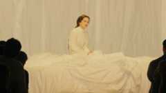 La cantante presentó un espectáculo de gran formato en la Sala Oval del MNAC, ante casi 900 espectadores. Aunque no habló ni cantó, su puesta en escena resultó tan impactante y sofisticada como su nuevo álbum, una "torre de Babel" musical en la que interpreta temas en 13 idiomas.Ni cantó ni habló. Permaneció más de una hora tumbada —a veces sentada al borde del escenario— como si aquel lugar fuera su cama. Parecía estar en la intimidad de su habitación, sola con sus pensamientos, escuchando un disco, moviendo las piernas, soltándose el pelo…Solo que su habitación, esta vez, era la inmensa Sala Oval del MNAC.Las únicas palabras del espectáculo aparecieron proyectadas sobre una gran tela blanca antes de que comenzara la experiencia sonora: "¿Cuándo fue la última vez que estuviste completamente a oscuras y en completo silencio? A veces, estar a oscuras es la mejor forma de experimentar la luz."A diferencia de las listening parties de Ciudad de México y Nueva York, en Barcelona Rosalía presentó un show de gran formato, escenográfico y deslumbrante, con la belleza visual y la sonoridad operística que definen su nuevo proyecto, LUX.