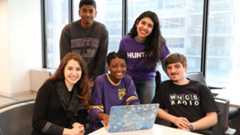 Hunter student wearing purple hunter hoodie in library