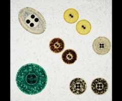 1200 A painting of nine button-resembling objects of various colors on a textured tan background.