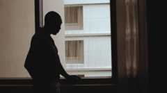 A man standing by a window in the dark
