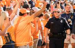 A uniformed UTPD officer walks past throngs of cheering football fans
