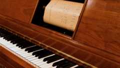 Player piano with a physical piano roll inside.