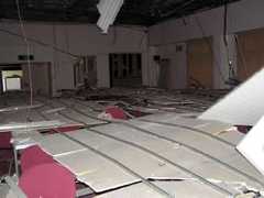 会議室の机の上に落下した天井。部屋の左右にかろうじて避難できるスペースが残されていた