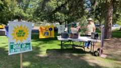Man poses with generators and Sun Day signs