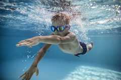 Image d'un enfant garçon avec des lunettes de natation en train de nager dans une piscine