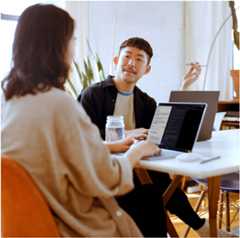 Two people in conversation while learning to code with Codecademy on their laptops