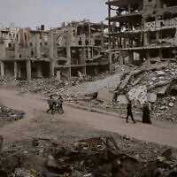 Palestinians walk among the ruins of destroyed buildings in Gaza City Monday, Nov. 24, 2025. (AP Photo/Jehad Alshrafi)