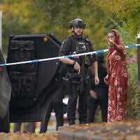 An armed police officer speaks to member of the public near the scene of terror attack at Heaton Park Hebrew Congregation synagogue, in Crumpsall, Manchester, England, on Yom Kippur, the holiest day of the Jewish year, October 2, 2025. (AP Photo/Ian Hodgson)