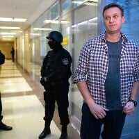Russian opposition leader Alexei Navalny speaks to the media in front of security officers standing guard at the Foundation for Fighting Corruption office in Moscow, Russia, Dec. 26, 2019. (AP Photo/Alexander Zemlianichenko, File)