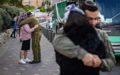 Israeli reserve soldiers kissing their wives goodbye in Jerusalem as they leave for their military service, May 5, 2025. (Chaim Goldberg/Flash90)
