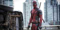 Deadpool (Ryan Reynolds) holding guns in both hands and standing next to a flipped car in Deadpool.