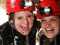 Two people in caving helmets laughing with water in background