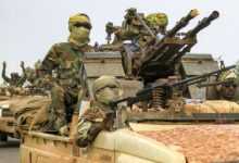 Fighters ride in a vehicle in a military convoy in Gedaref, Sudan