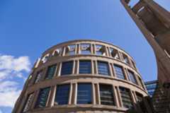 A colour photograph of a round building resembling the architecture of the Colosseum in Rome but clearly contemporary with its glass windows on the top two floors.