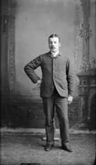Black-and-white portrait of a man standing in a photo studio.