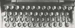 Photograph showing the keys of a manual typewriter. Each of the keys, which are black, has two characters in syllabics that are white.