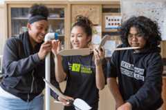 Three students assembling a model wind turbine.