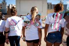 Feminine people standing next to each other, all wearing white, pink and blue butterfly wings.