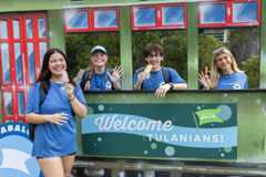 Smiling students, three waving from a "Welcome Tulanians!" green streetcar booth.