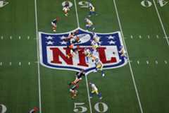 NFL players from two teams, one in orange and black and the other in yellow and blue, line up on the field near the 50-yard line, with the NFL logo visible at midfield.