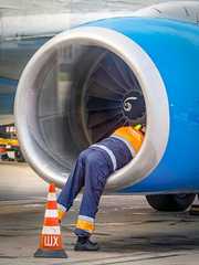 An aircraft technician performs maintenance on an airliner engine