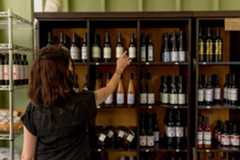 Woman reaching for a wine bottle on a shelf