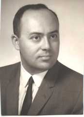 A black and white portrait of Andrew Viterbi taken in 1963. He is wearing a suit with a white shirt and a dark tie. Andrew has a serious expression and is looking slightly to the side.
