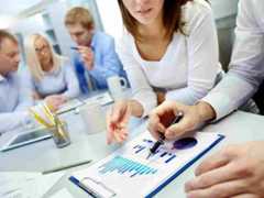 5 professionals at conference table discussing reports