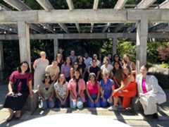 Group of KIND staff posing outside and smiling on a sunny day.