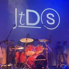 John the Drum School logo projected on to backdrop above drum kit