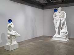 Two Koons statues with a blue ball balanced on their shoulders.