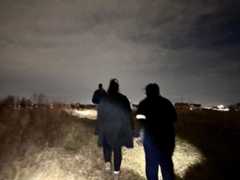 Volunteers walk down a path outside at night