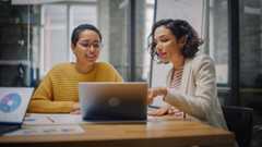 two women at a table with data charts