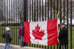 Toronto residents Douglas Bloomfield, from right, his son Phoenix and wife Ame, who are on vacation in Washington, hold a Canadian flag and an ice hockey stick to show their support for Canada regarding trade tariffs in front of the White House in Washington, Thursday, March 13, 2025. (Ben Curtis/AP)