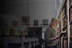 studerande läser bok vid hyllan