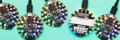 Five round circuit boards in a row, with rainbow LEDs, one is upside down and says Circuit Playground on back