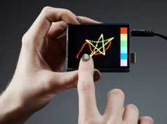 Hand holding up a capacitive touch screen, another hand doodling on the screen